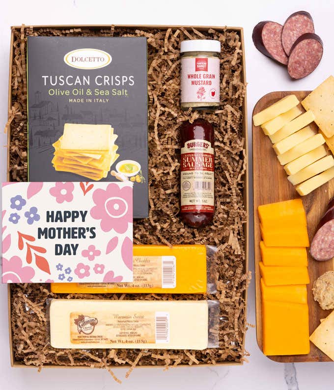 A snack and wine gift box featuring 2 cheeses - chaddar & Swiss, cracker crisps, summer sausage, mustard, and a bottle of red wine. A 'Happy Mother's Day,' sits on top. A perfect gift for Mom.