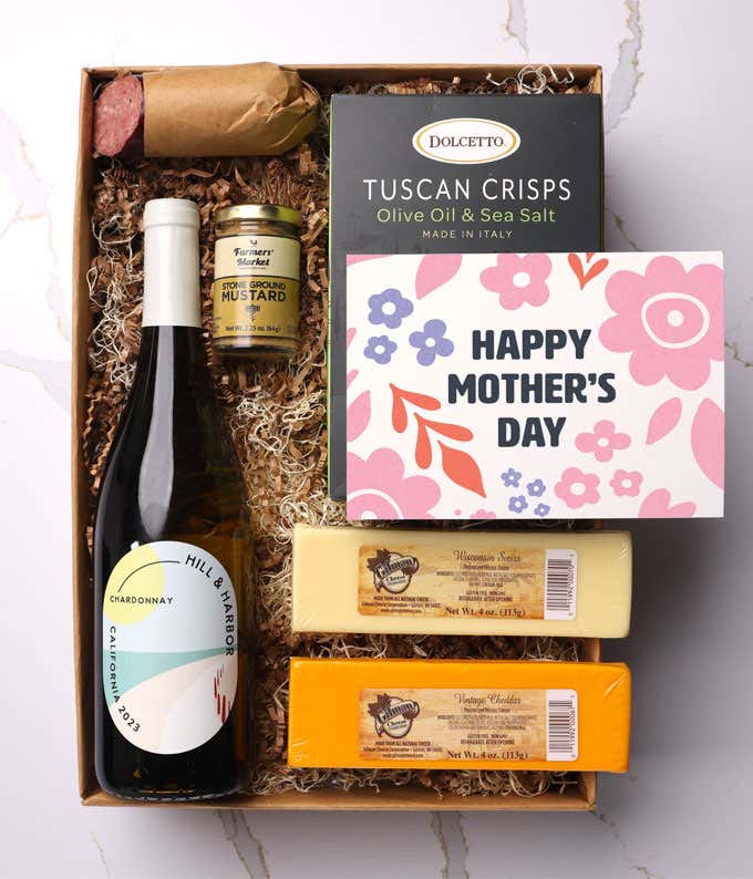 A snack and wine gift box featuring 2 cheeses - chaddar & Swiss, cracker crisps, summer sausage, mustard, and a bottle of white wine. A 'Happy Mother's Day,' sits on top. A perfect gift for Mom.