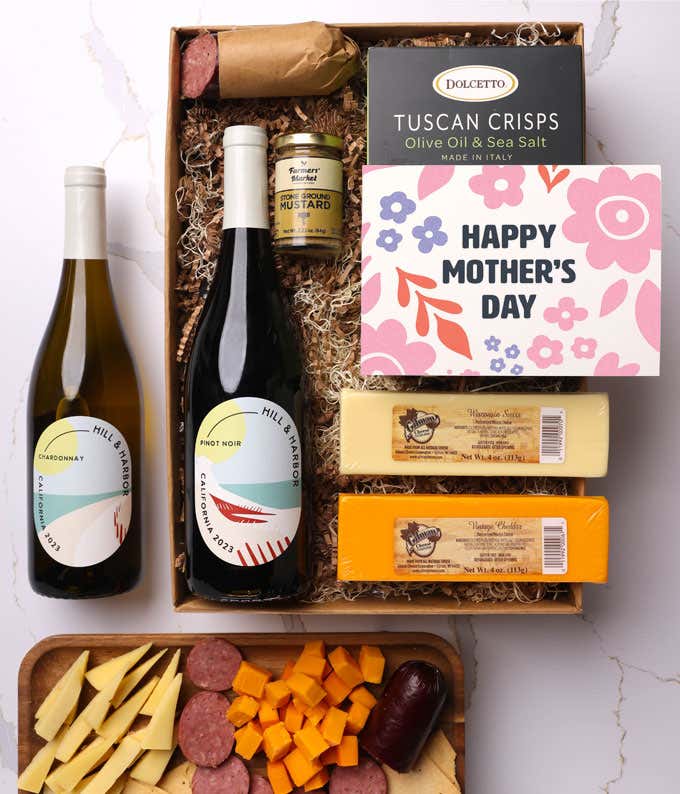 A snack and wine gift box featuring 2 bottles of wine - red and white, 2 cheeses - chaddar & Swiss, cracker crisps, summer sausage, and mustard. A 'Happy Mother's Day,' sits on top. A perfect gift for Mom.