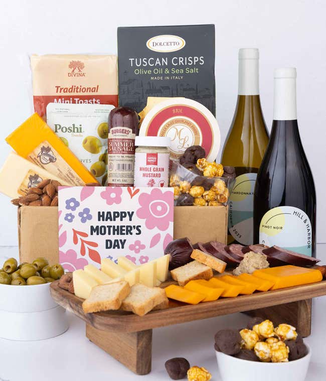 A charcuterie spread with 3 cheeses, sausage, olives, crackers, mustard, almonds, and chocolate finished with bottle of red &amp; white wine and 'Happy Mother's Day' card.
