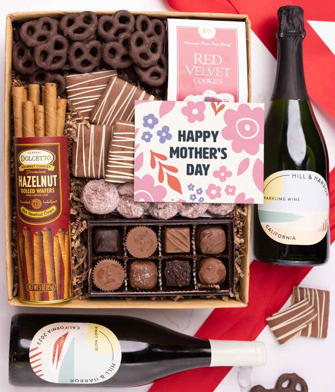 Bottles of Hill & Harbor Pinot Noir and Sparkling wine paired with chocolate covered pretzels, mini chocolate chip cookies, a box of chocolates, and a 'Happy Mother's Day' card.