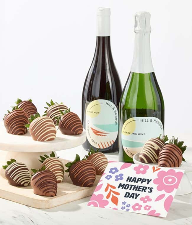 Hill &amp; Harbor Pinot Noir and sparkling wine bottles displayed with two glasses and assorted chocolate-covered strawberries on trays, styled with a floral Happy Mother&rsquo;s Day card for a premium wine gift.