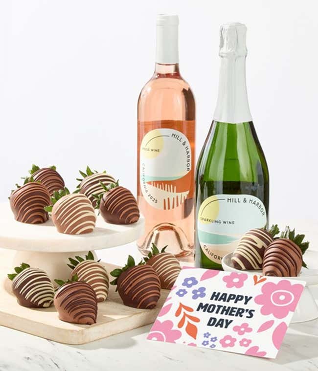 Hill &amp; Harbor ros&eacute; and sparkling wine bottles displayed with two glasses and assorted chocolate-covered strawberries on trays, styled with a floral Happy Mother&rsquo;s Day card for a festive wine gift.