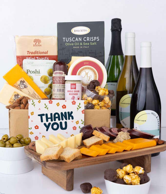 A wine and cheese gift set featuring bottles of Hill & Harbor sparkling wine, Chardonnay, and Pinot Noir. Includes a variety of gourmet cheeses, crackers, olives, summer sausage, almonds, salami, and condiments finished with a Thank You card.